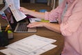 Midsection of caucasian woman sitting at table working at home, using laptop and holding paperwork Royalty Free Stock Photo