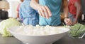 Midsection of diverse group of friends preapring meal, chopping vegetables in kitchen, slow motion