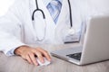 Midsection of doctor using laptop and mouse at desk Royalty Free Stock Photo