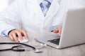 Midsection of doctor using laptop and mouse at desk Royalty Free Stock Photo