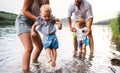 A midsection of family with two toddler children outdoors by the river in summer. Royalty Free Stock Photo