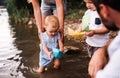 A midsection of family with two toddler children outdoors by the river in summer. Royalty Free Stock Photo