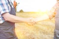 Midsection of farmers shaking hands while standing on field at farm