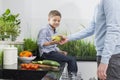 Midsection of father giving pear to son in kitchen