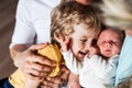 Midsection of father with newborn baby and small toddler son at home.