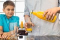 Midsection of father serving orange juice for son in kitchen