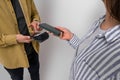 Midsection of female customer scanning her smart phone on credit card machine held by male clerk against background. Woman making Royalty Free Stock Photo