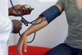 Midsection of frican american male doctor measuring blood pressure of biracial female patient