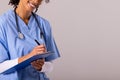 Midsection of happy african american mid adult female doctor with stethoscope writing on clipboard Royalty Free Stock Photo