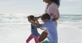 Midsection of happy hispanic moter with daughter and son walking on beach