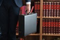 Lawyer Carrying Briefcase Against Bookshelf