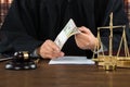 Corrupt Judge Holding Dollar Bundle At Desk Royalty Free Stock Photo