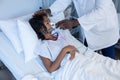 Midsection of male doctor putting oxygen mask ventilator on sick mixed race girl in hospital bed Royalty Free Stock Photo