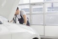 Midsection of male technician repairing car engine in workshop