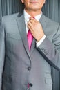 Midsection of mature businessman adjusting necktie
