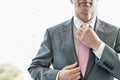 Midsection of mature businessman adjusting necktie