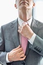 Midsection of mature businessman adjusting tie