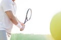 Midsection of mature man hitting tennis ball against clear sky