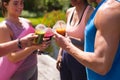 Midsection of men and women toasting healthy drinks in disposable cups post outdoor workout