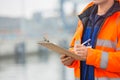 Midsection of mid adult man writing on clipboard in shipping yard