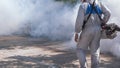 Midsection of outdoor healthcare worker using fogging machine spraying chemical to eliminate mosquitoes in public area