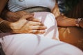 photograph of hands of pregnant wife and hands of her husband touching her belly