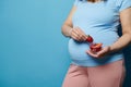 Midsection of a pregnant woman in blue t-shirt, holding glass bowl with sweet strawberries,  on blue background Royalty Free Stock Photo