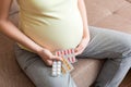 Midsection of pregnant woman taking vitamin pill on sofa at home Royalty Free Stock Photo