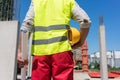 Midsection rear view of a worker holding a blueprint and a yellow hard hat Royalty Free Stock Photo