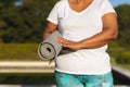 Midsection of senior african american woman with yoga mat by outdoor pool in countryside