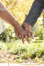 Midsection of senior biracial bride and groom holding hands at sunny outdoor wedding ceremony