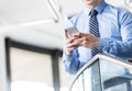 Midsection of smiling businessman using smartphone while standing at office Royalty Free Stock Photo