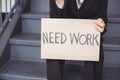 Midsection of unemployed businesswoman with need work placard