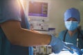 Midsection view of surgeon holding surgical equipment over the operating table