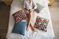 Midsection view of woman with night shirt sitting indoors on bed, holding coffee.