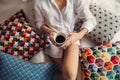 Midsection view of young woman with night shirt sitting indoors on bed in the morning.