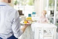 Midsection of waiter serving lunch to mature customer sitting at table in restaurant