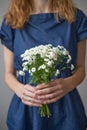 midsection woman in a dark blue dress holding a bouquet of white flowers in her hands. Spring concept.