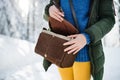 Midsection of woman with handbag standing outdoors in snowy winter forest.