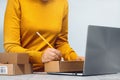 Midsection of a woman writing on a cardboard box. despatch