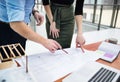 Midsection of young architects with blueprints and model of a house standing in office. Royalty Free Stock Photo