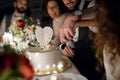 A midsection of young couple sitting at a table on a wedding, cutting a cake. Royalty Free Stock Photo