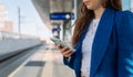 Midsection. Young stylish woman using mobile while waiting for train at station. Public transport.