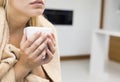 Midsection of young woman holding coffee mug in house