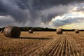Field with hay bales under stormy sky and rays of light Royalty Free Stock Photo