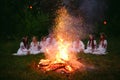 Midsummer night. Young people in Slavic clothes sitting near the bonfire