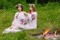 Midsummer. Two girls in the Slavic clothes weave braids in the hair near the fire Royalty Free Stock Photo