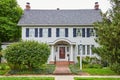 Midwest American large white house with blue shutters and mahogany door on summer day