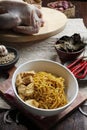 Mie Ayam Yamin or Yamin chicken noodles are served in a bowl placed on a saucer, decorated with beef on a wooden table. Top View