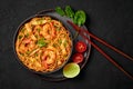 Mie Goreng in black bowl on dark slate table top. Indonesian cuisine prawn noodles and vegetables stir fired dish